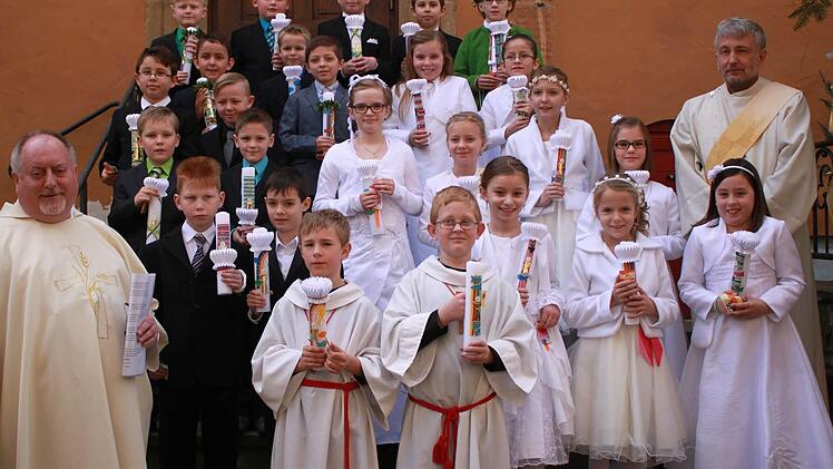 Ebern &mdash; Pater Rudolf Theiler (links) und Diakon Uwe Holschuh (rechts) begleiteten in Ebern 25 Kinder erstmals zum Tisch des Herrn. Die 16 Jungen und neun M&auml;dchen empfingen in einem Gottesdienst in der Stadtpfarrkirche zum ersten Mal den Leib des Herrn. Foto: Katharina Becht