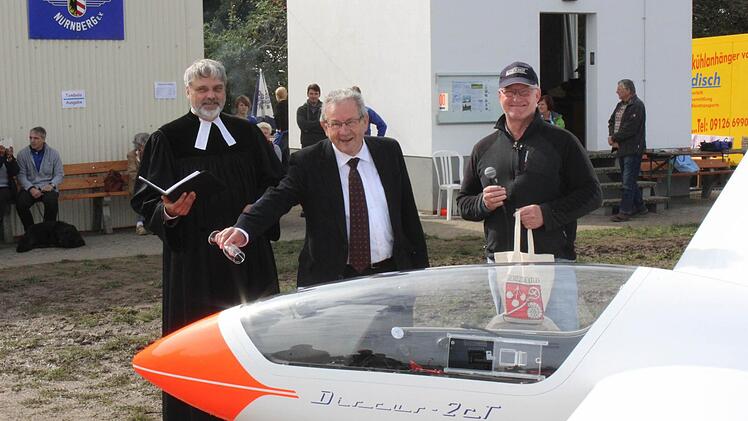 Pfarrer Bertholdt, Bürgermeister Schmidtlein und Franz Maier (v.l.) taufen ein Flugzeug.