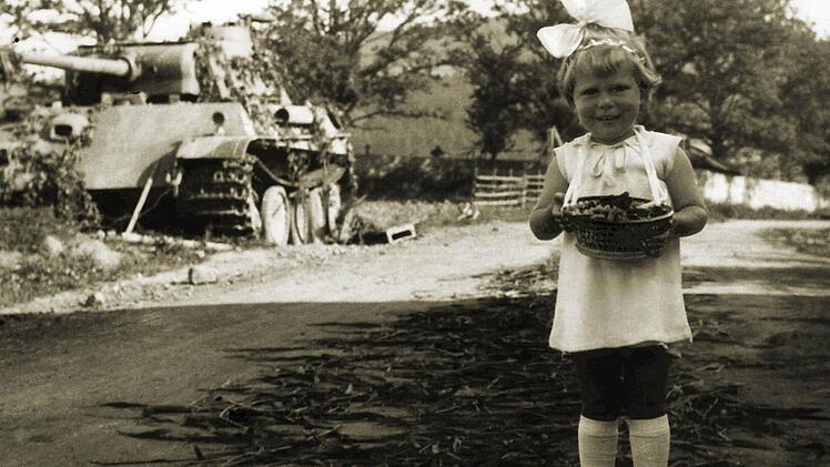 Das Leben geht weiter: Blumenmädchen neben zerstörtem Panzer.