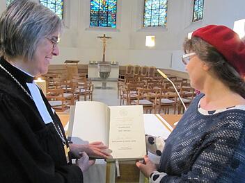 Erika Kienel vom Kirchenvorstand freut sich über die neue Altarbibel mit der neu überarbeiteten Übersetzung von Martin Luther für die Heilig-Kreuz-Kirche. Die Bibel brachte Regionalbischöfin Dorothea Greiner zur Herbsttagung der Dekanatssynode mit. Foto: Martin Koch
