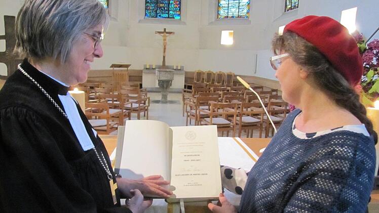 Erika Kienel vom Kirchenvorstand freut sich über die neue Altarbibel mit der neu überarbeiteten Übersetzung von Martin Luther für die Heilig-Kreuz-Kirche. Die Bibel brachte Regionalbischöfin Dorothea Greiner zur Herbsttagung der Dekanatssynode mit. Foto: Martin Koch