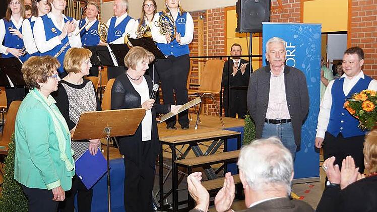Joachim Meixner (rechts) bekam aus der Hand der Vorsitzenden des Kreisverbands Bamberg des Nordbayerischen Musikbundes, Angelika Becher (mit Mikrofon), die Urkunde überreicht. Foto: Johannes Michel