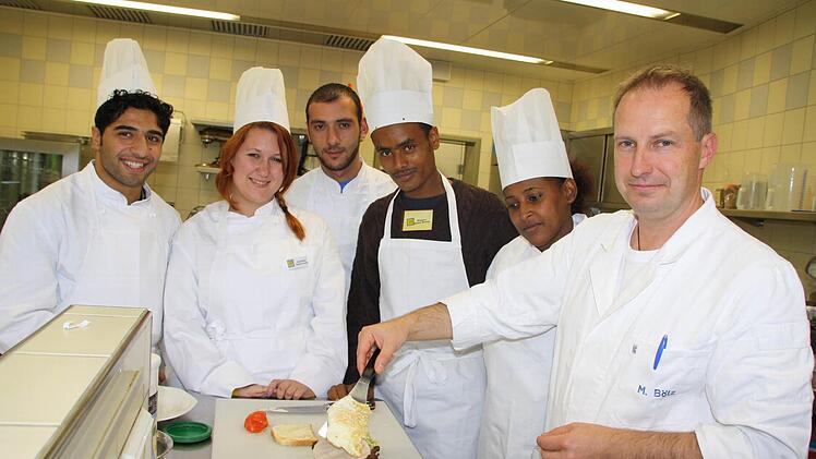 Wenn Fachlehrer Markus Bötz (rechts) mit Asylbewerbern wie Omidreza Fayzeyab (links) oder Kumengr Getahun Mulesa (2. von rechts) ein Sandwich zubereitet, dann geht es weniger um ausgefeilte Kochkünste als um Vokabeln und den Umgang mit der deutschen Sprache. Fotos: Ralf Ruppert
