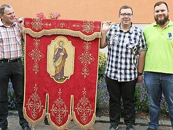 Michael Roppelt (Zweiter von rechts) hat die wieder aufgetauchte Bürgerfahne im Fronleichnamszug getragen. Sein Bruder Stefan (rechts) stellt sich ebenfalls als Fahnenträger zur Verfügung. Mesner Werner Kaiser (links) brachte den Stein ins Rollen. Foto: Evi Seeger