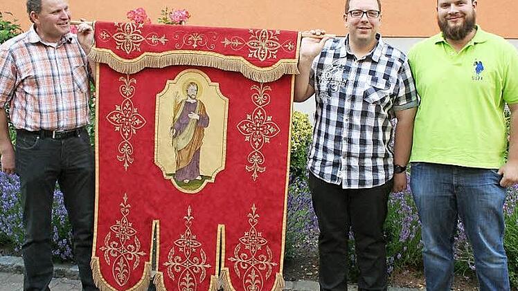 Michael Roppelt (Zweiter von rechts) hat die wieder aufgetauchte Bürgerfahne im Fronleichnamszug getragen. Sein Bruder Stefan (rechts) stellt sich ebenfalls als Fahnenträger zur Verfügung. Mesner Werner Kaiser (links) brachte den Stein ins Rollen. Foto: Evi Seeger