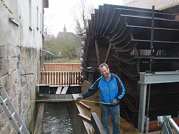 Helmut Vorndran vor dem kürzlich installierten Mühlrad, das mit Computertechnik gesteuert wird und Strom erzeugt. Fotos: Matthias Einwag