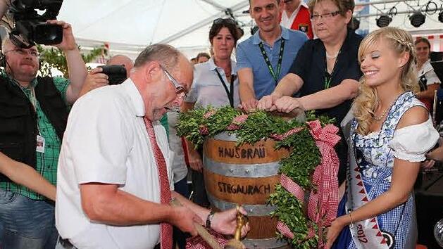 Mit zwei kr&auml;ftigen Hieben sticht B&uuml;rgermeister Werner Hipelius im Festzelt das erste Kirchweih-Fass an.  Foto: RiegerPress