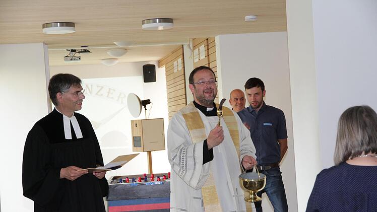 Die beiden Pfarrer Daniel Schuster und Christian Muschler (links) segnen den Dorftreff Eggolsheim. Foto: Mathias Erlwein