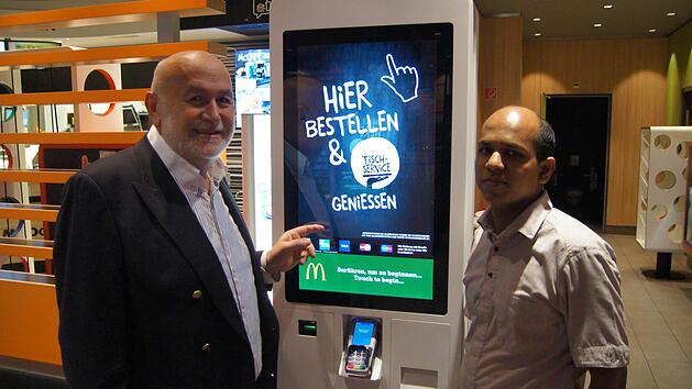 Franchise-Nehmer Dr. Josef Neumair (links) mit dem Mitarbeiter Herrn Thevarajan Jude an einem der digitalen Bestell-Terminals. Foto: McDonald&acute;s