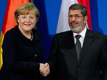 Bundeskanzlerin Angela Merkel (CDU) und Ägyptens Präsident Mohammed Mursi geben sich bei einer Pressekonferenz die Hand. Foto: Sven Hoppe/dpa