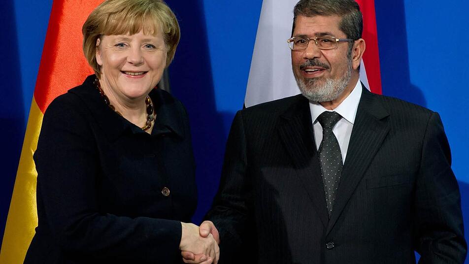 Bundeskanzlerin Angela Merkel (CDU) und Ägyptens Präsident Mohammed Mursi geben sich bei einer Pressekonferenz die Hand. Foto: Sven Hoppe/dpa