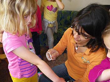 In der Kindertagesstätte in Maßbach ist eine Lupe immer griffbereit. Erzieherin Sandra Wenzel schaut bei der kleinen Nina, ob sie sich beim Spielen im Garten eine Zecke geholt hat. Foto: Barbara Conhoff