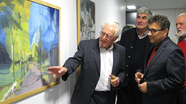 Robert Reiter (links) erläutert Bürgermeister Rolf Rosenbauer bei einem Rundgang durch die Vernissage vor zahlreichen interessierten Besuchern seine Werke - das Gemälde zeigt die Pappelallee in Meschenbach.     Foto: Norbert Karbach