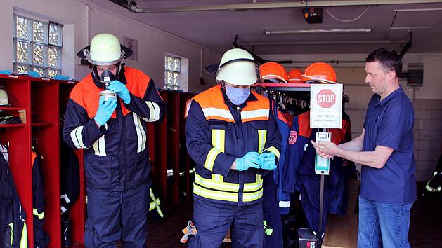 Vorbereitung auf den Einsatz in Corona Zeiten Einsatz (von rechts) 1. H&auml;nde desinfizieren (Kommandant Bernd Ort);  2. Handschuhe und Gesichtsmasken anlegen (Ger&auml;tewart Florian Weing&auml;rtner);  3. Schutzkleidung mit Atemschutzmaske anziehen (2. Kommandant Tobias Dittrich). Foto: Werner Vogel