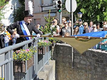 Der jüngste Stadtrat Sven Hofmann beim traditionellen Fahnenschwenken auf der Schwedenbrücke.  Fotos: Michael Wunder
