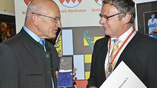 Bezirkstagspräsident Günther Denzler hat Siegfried Küspert die Ehrenmedaille des Bezirks umgehängt.