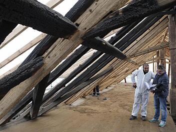 Architekt Peter Fluhrer (rechts) bespricht sich mit einem der Arbeiter, die in Schutzanzügen den Rußniederschlag auf dem Spitzboden entfernt haben. Foto: Matthias Hoch