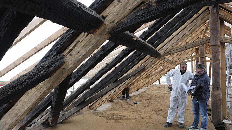 Architekt Peter Fluhrer (rechts) bespricht sich mit einem der Arbeiter, die in Schutzanzügen den Rußniederschlag auf dem Spitzboden entfernt haben. Foto: Matthias Hoch