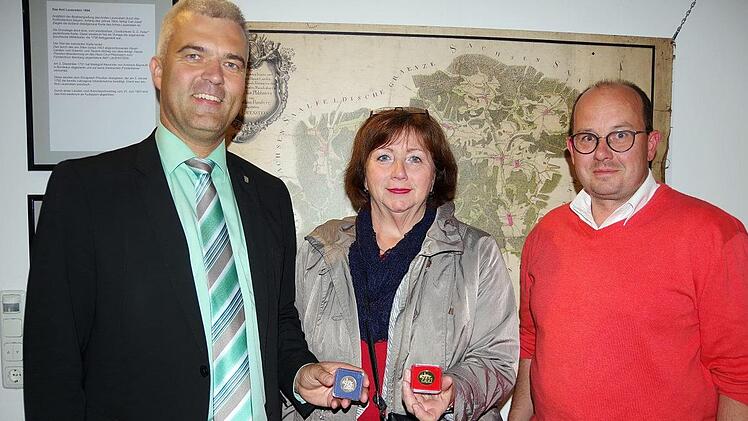 Im Rahmen der Ausstellungseröffnung präsentierte Bürgermeister Timo Ehrhardt die anlässlich des Jubiläums zu erwerbenden Gedenkmünzen. Erworben werden können die Taler beim 750-Jahr-Markt am Sonntag, wenn diese von einem Münzpräger vor Ort geprägt werden. Silber- und Goldmünzen müssen beim Münzpräger vorbestellt werden. Dies kann bereits im Vorfeld über Manja Hünlein bei der Stadt Ludwigsstadt erfolgen. Das Bild zeigt von links Bürgermeister Ehrhardt, 2. Bürgermeisterin Eva Jahn und Stadtrat ...