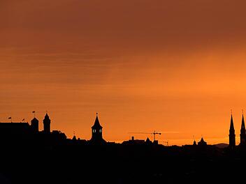Die Silhouette der (l) Kaiserburg und die Türme der Kirche St. Sebald (r) sind vor dem Morgenhimmel in Nürnberg zu erkennen. Foto: Daniel Karmann/dpa