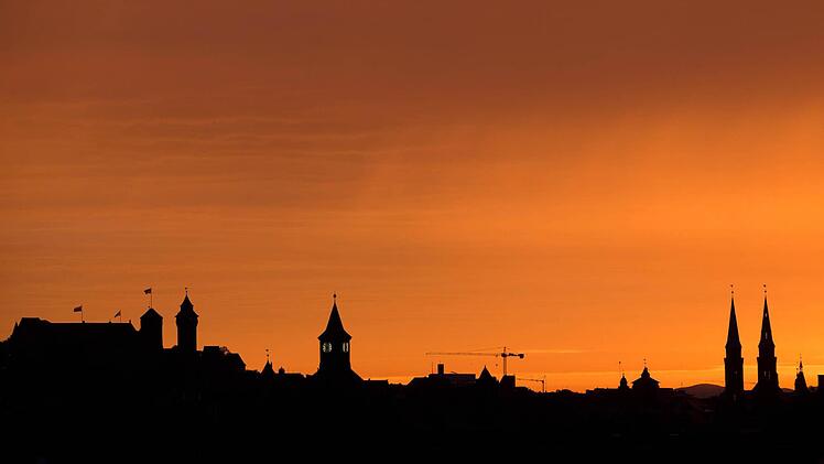 Die Silhouette der (l) Kaiserburg und die Türme der Kirche St. Sebald (r) sind vor dem Morgenhimmel in Nürnberg zu erkennen. Foto: Daniel Karmann/dpa