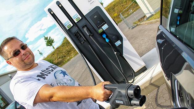 J&uuml;rgen Frey tankt sein Elektrofahrzeug an der Ladestation auf dem Ha&szlig;furter Norma-Parkplatz auf. Wie viel das Akkuladen am Ende kostet, ist bei vielen Ladestationen aber vorher nicht ersichtlich. Foto: Teresa Hirschberg