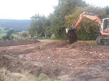 Die Vorarbeiten für den künftigen Parkplatz am Friedhof in Platz haben bereits begonnen. Momentan wird die benötigte Fläche eingeebnet. Dort soll es später rund 20 neue Stellplätze geben, die mit Rasengitter befestigt werden.  Foto: Rolf Pralle