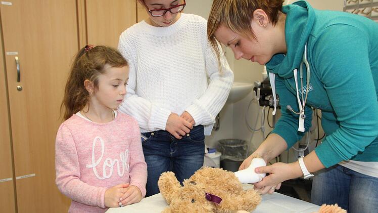 Darf niemals fehlen: Die Sprechstunde für Puppen und Teddys. Ärztin Tünole Szemcsak mit Marie (links) und Celine beim Teddy-Verbinden. Foto: Ulrike Müller
