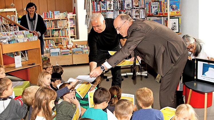 Landrat Wilhelm Schneider und Mohamad Almotlak (von rechts) lasen vor den Kindern in der Zeiler Bibliothek in zwei Sprachen.  Foto: Günther Geiling