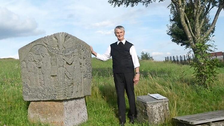 Pfarrer Reinhard Stauch am Bildstock in Kehlbach unweit der Marienkirche, den er anlässlich seines 25-jährigen Priesterjubiläums vom Akademischen Bildhauer Heinrich Schreiber gestalten ließ. Das Motiv berührt ihn noch heute zutiefst.  Foto: K.- H. Hofmann