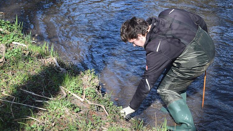 Stellvertretender Jugendleiter Dominik Krautwurst zieht ein Stück Plastik aus dem Fluss. Foto: Daniela Pondelicek