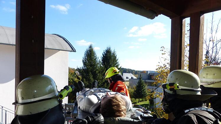 Auf der Trage liegend wird die verletzte Person vom Balkon auf dem Rettungskorb geschoben. Foto: Klaus-Peter Wulf