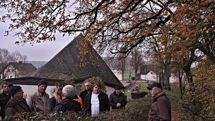 Ein "kritischer Baum" und Äste (rechts) "bedrohen" das Leichenhaus auf dem Friedhof in Gemeinfeld. Hier sollte Abhilfe geschaffen werden. Bürgermeister Hermann Niediek (Dritter von rechts) nahm das zur Kenntnis.Helmut Will