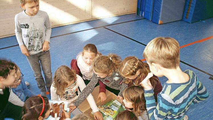 Begeistert öffnen die "Leseraben-Gewinner" das Paket mit Büchern und Spielen, das sie für ihren 5. Platz erhalten haben. Foto: Susanne Deuerling