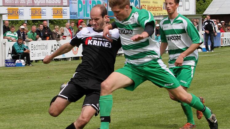 Der Sander Florian Gundelsheimer (links) zieht den Ball von der 16-Meter-Linie vors Tor, Gästespieler Björn Schönwiesner kann seinen Fuß nicht mehr dazwischen halten.