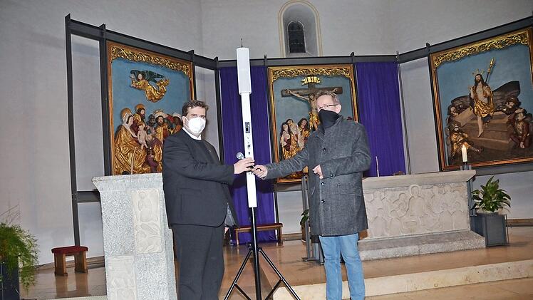 Kirchenpfleger Mathias Beetz überreicht das Mikrofon der neuen Beschallungsanlage in der St.-Bartholomäus-Kirche an Pfarrer Detlef Pötzl, der sie in Betrieb nahm.  Foto: K.-H. Hofmann