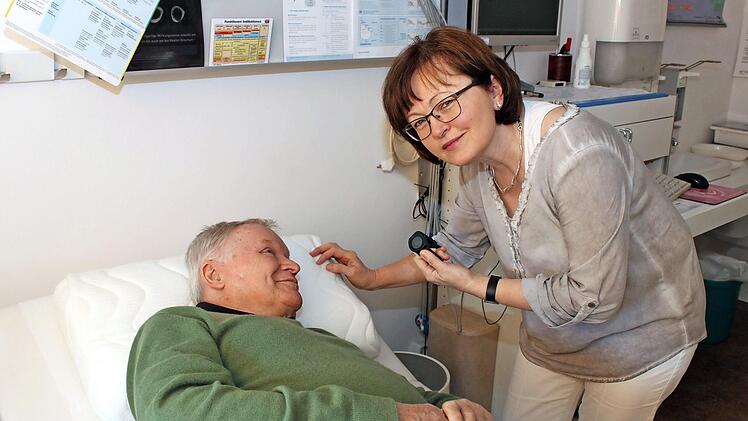 Gabriele Brütting erklärt einem Patienten das Schlafkissen.