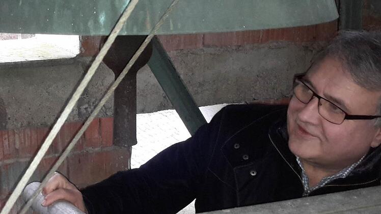 Pfarrer Gerd Kirchner nimmt unter der engen Turmspitze die zum Teil marode Glockenanlage in Augenschein. Foto: Rolf Pralle