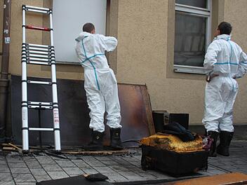 Am Montagvormittag schrauben zwei Männer in weißen Anzügen eine Platte gegen das Fenster.  Foto: Lisa Kieslinger