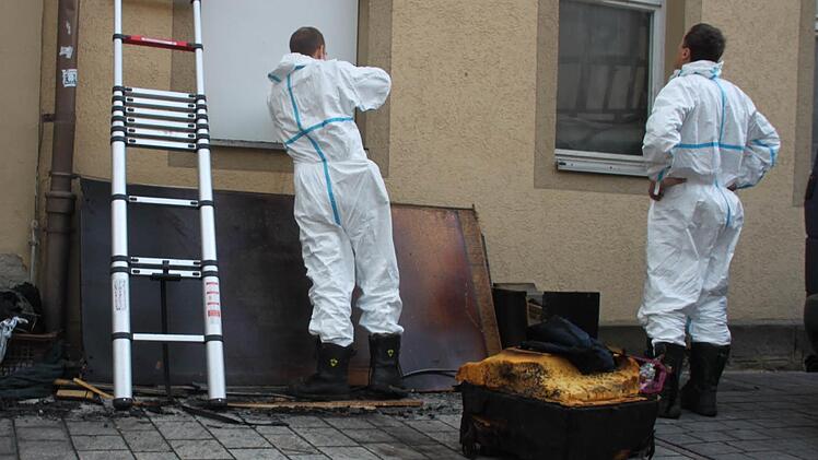 Am Montagvormittag schrauben zwei Männer in weißen Anzügen eine Platte gegen das Fenster.  Foto: Lisa Kieslinger