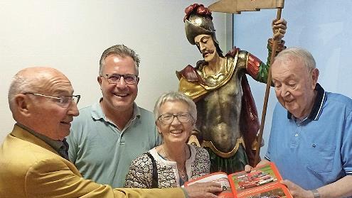 Ehrenmitglied und Alt-Bürgermeister Hans Lang (l.) und seine Frau Helga sowie Vorsitzender Thomas Geiger lassen sich von Karl-Heinz Schalk (r.) den Inhalt des neuen Buchs erläutern. Im Hintergrund wacht St. Florian mit Argusaugen darüber.