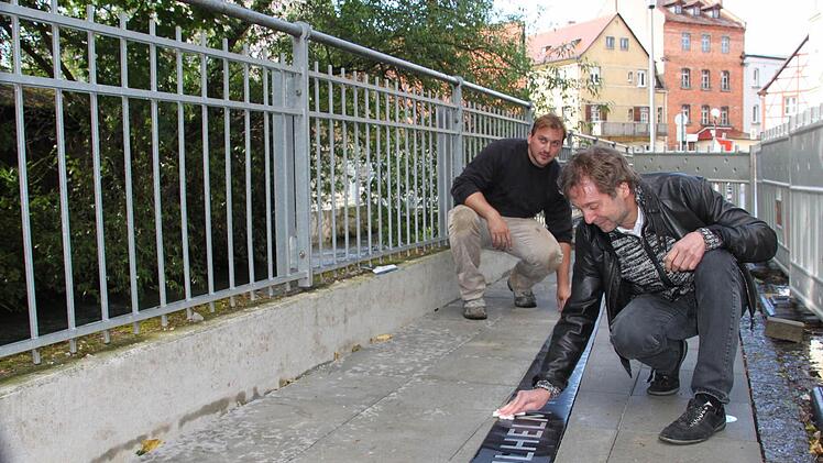 Der Künstler Harald Winter poliert sein Kleemann-Kunstwerk im Forchheimer Kleemann-Weg. Im Hintergrund der Bildhauer-Meister Sebastian Bertholdt, der Winters Werk handwerklich umsetzte. Foto: Roepert
