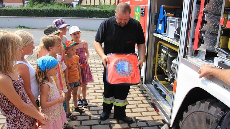 Jugendfeuerwehrwart Udo Schwappach erklärt den Kindern wie ein Feuerwehrauto ausgerüstete ist und machte dann mit ihnen eine kurze "Spritztour" durch den Ort.