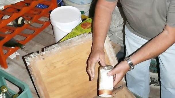 Milbenfütterung. In der Holzkiste liegen Käserollen auf einer Schicht Milben. Damit diese nicht im Laufe der Zeit den ganzen Käse auffressen, füttert Alois Voigt  seine Lieblinge täglich mit etwas Roggenmehl.