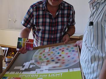 Armin Haas (rechts) und Gerd Kirchner sind begeistert, als sie die frisch gedruckten Plakate zur Ausstellung "Spuren zum Licht" auspacken.