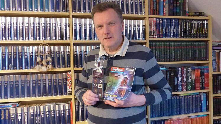 Hubert Haensel aus Waldershof mit dem "Perry Rhodan"-Heft 2840, in dem er seine Naschkatze ein Stück Lauensteiner Edel-Vollmilch essen lässt, und mit Pralinen, die an seinem Arbeitsplatz selten fehlen. Foto: privat