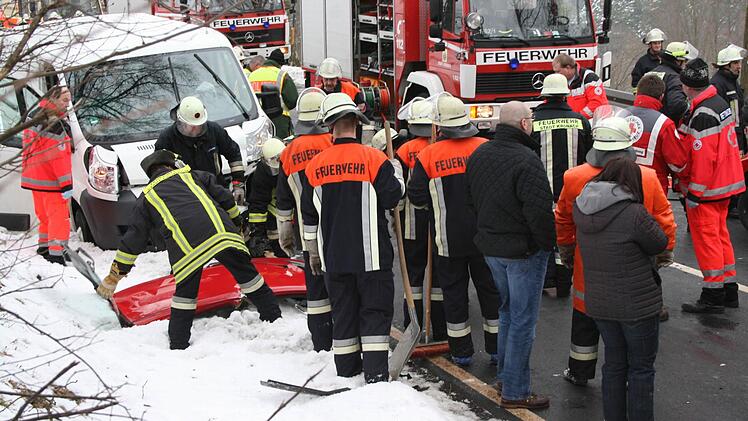 Feuerwehrleute legen das abgeschnittene Kleinwagendach ab.