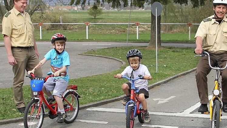Eine Zufallsbekanntschaft mit Folgen: Eigentlich wollten Julian (acht Jahre, links) und Jonas (fünf Jahre) unter Aufsicht ihrer Eltern nur ein paar Runden auf dem Verkehrsübungsplatz in Knetzgau drehen. Plötzlich standen die Verkehrserzieher Dominique Heim (links) und Manfred Stühler (rechts) auf dem Platz - und einer fuhr auch noch mit.  Foto: Katja Kölbl
