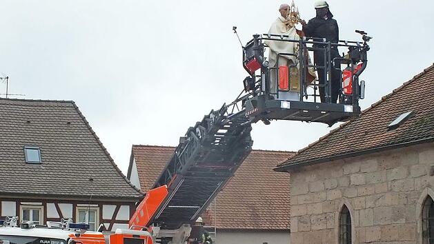Pfarrer Helmut Hetzel spendete den Eucharistischen Segen von der Drehleiter der Feuerwehr aus. Foto: Manfred Welker