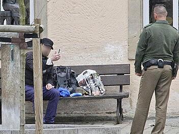 Der Mann zeigt sein Messer, das er immer wieder in die Parkbank rammte. Foto: Josef Hofbauer